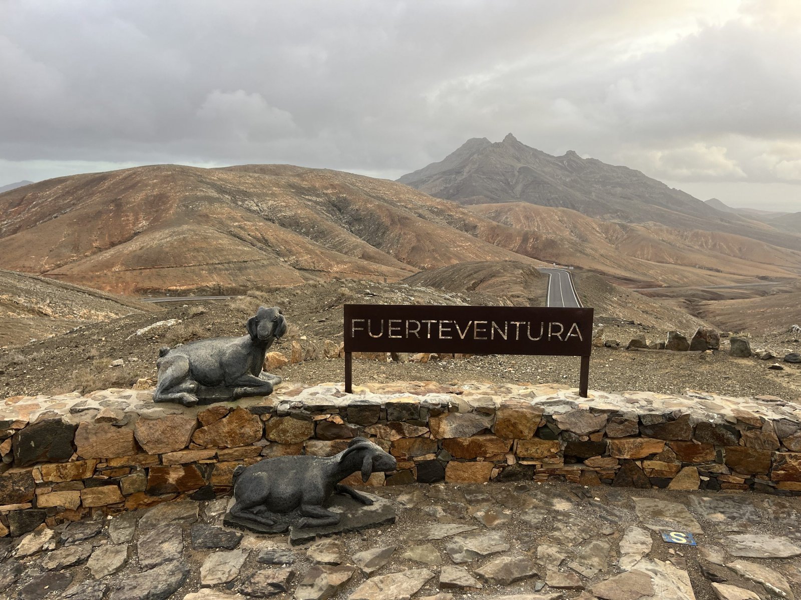 Cartel de Fuerteventura con cabras majoreras y paisaje árido del interior de la isla
