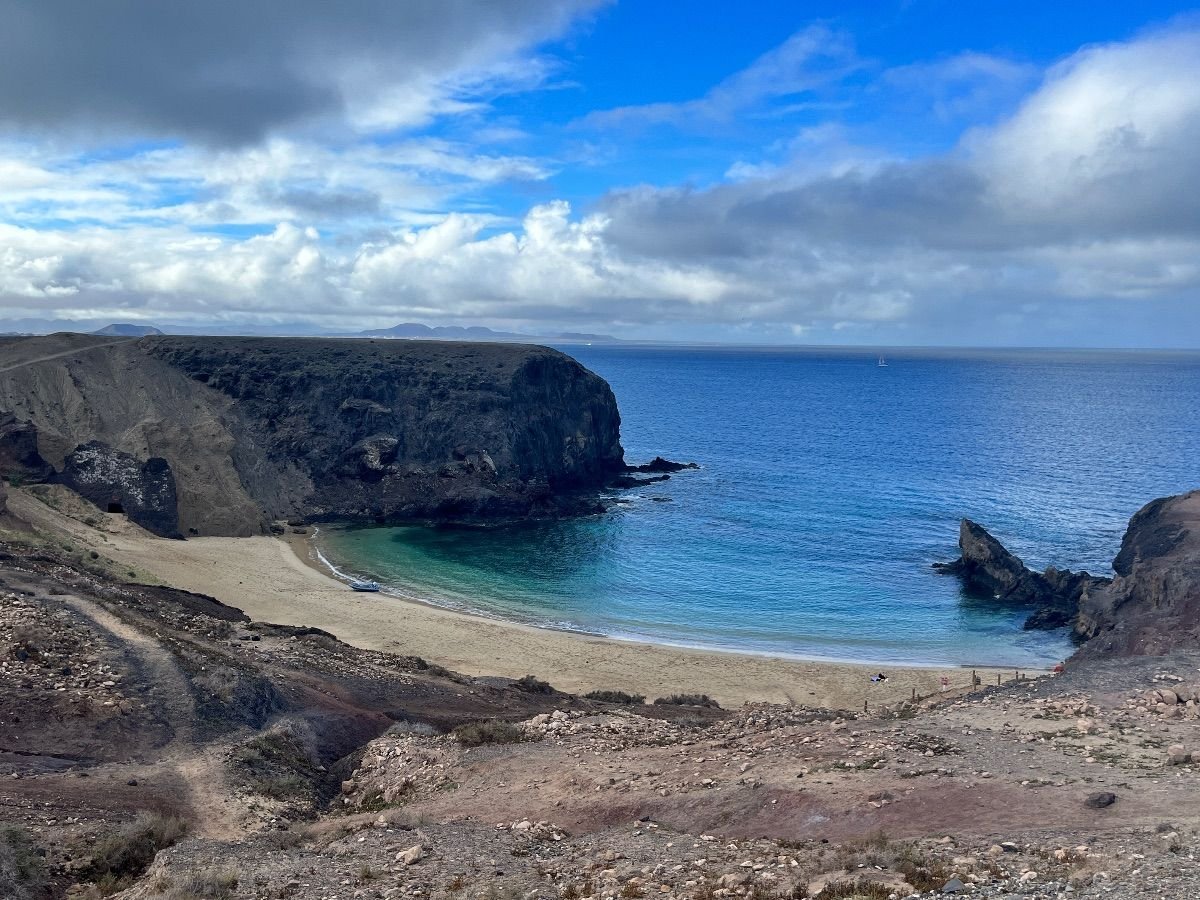 Vista panorámica de la Playa de Papagayo en Lanzarote, con su arena dorada y aguas turquesas rodeadas de acantilados volcánicos.