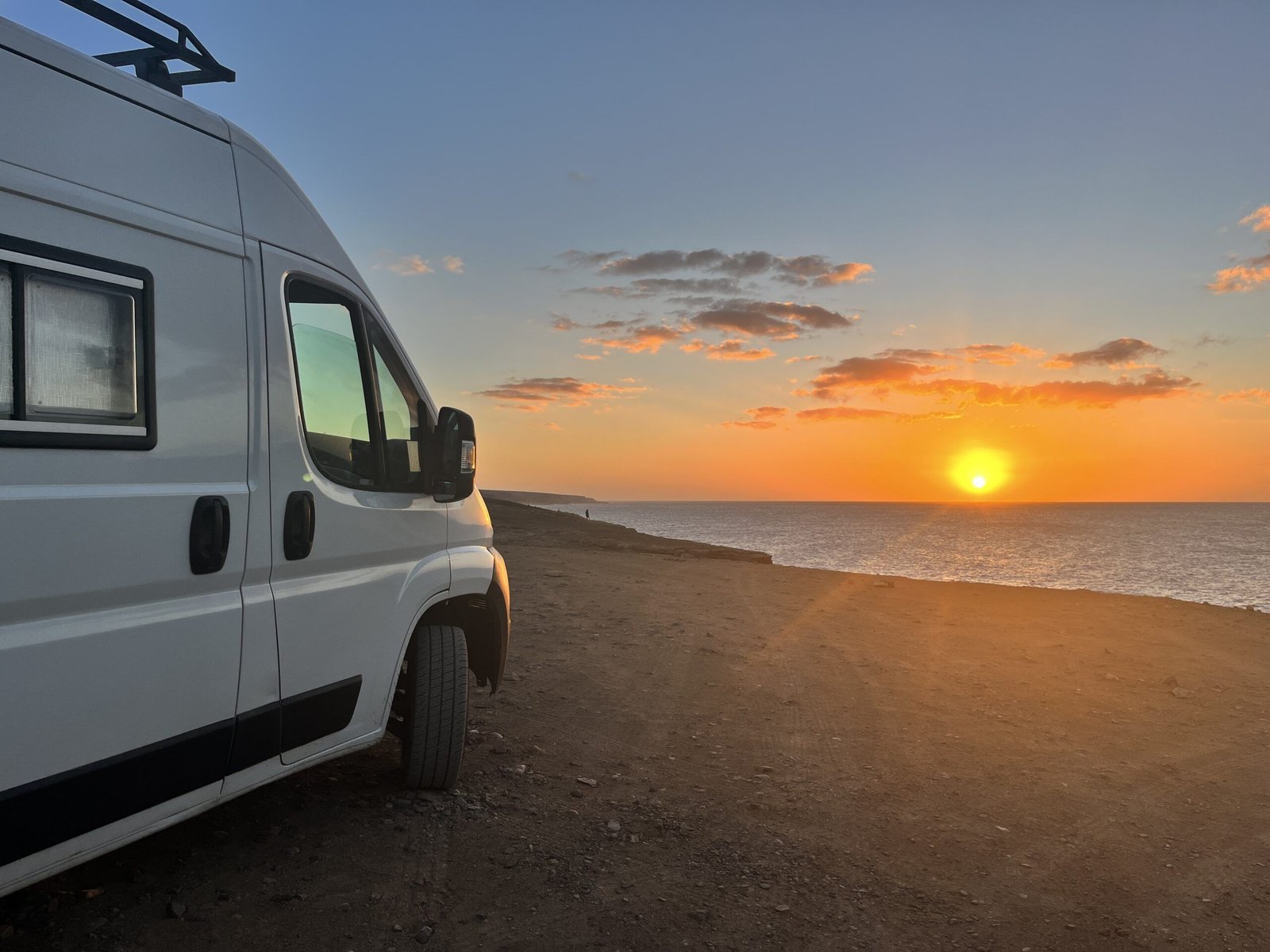 Furgoneta camper junto al mar durante un atardecer en ruta, imagen de viaje en camper 2025