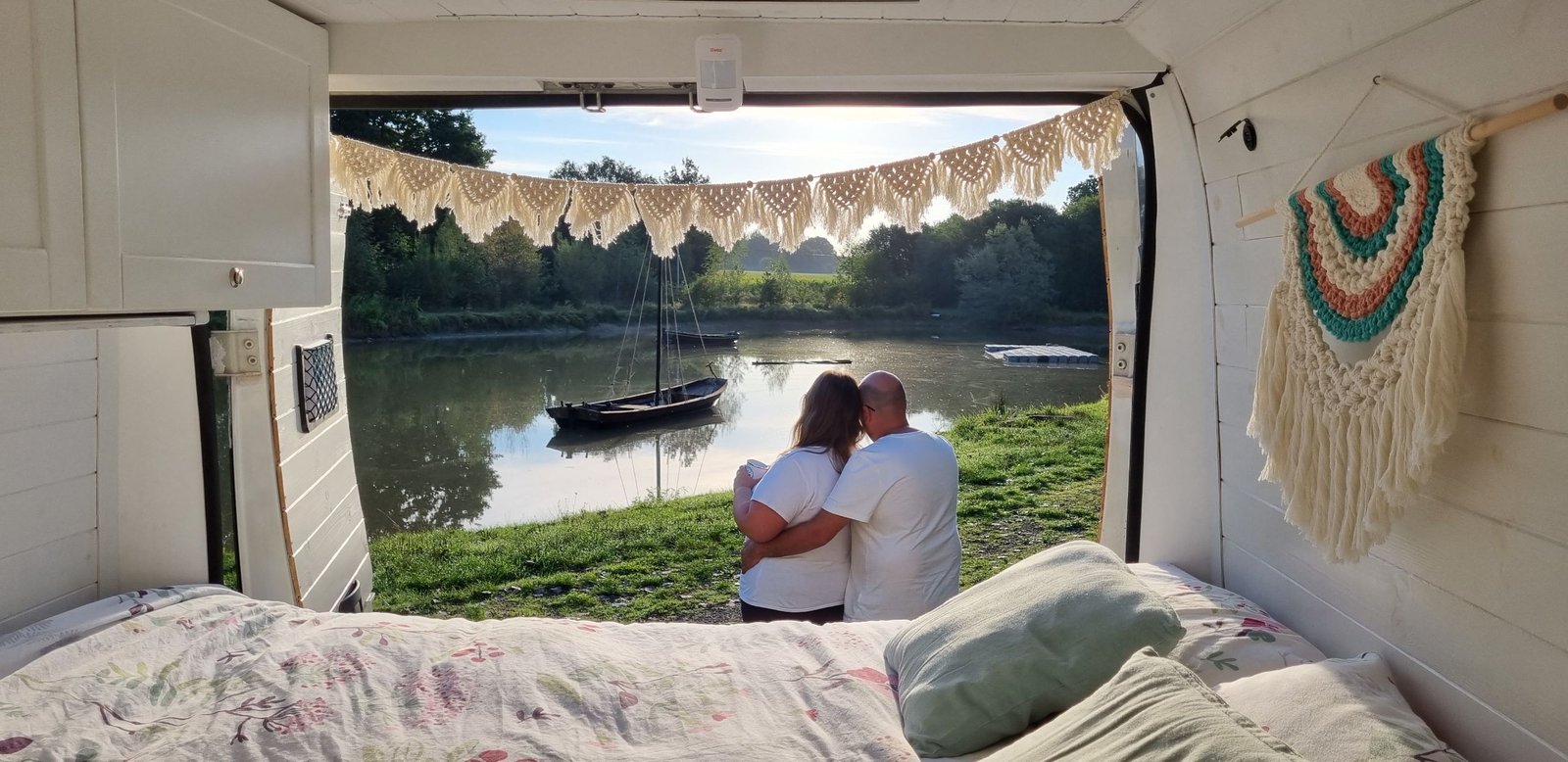 Personas junto a su furgoneta camper con vistas a un lago durante un viaje, imagen de portada del post sobre apps para viajar en camper