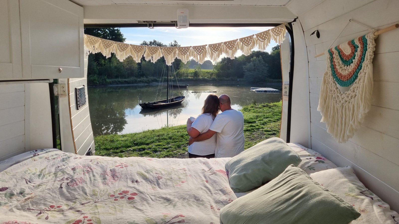 Pareja frente a su camper con vistas a un lago en Europa durante un viaje en furgo en 2025