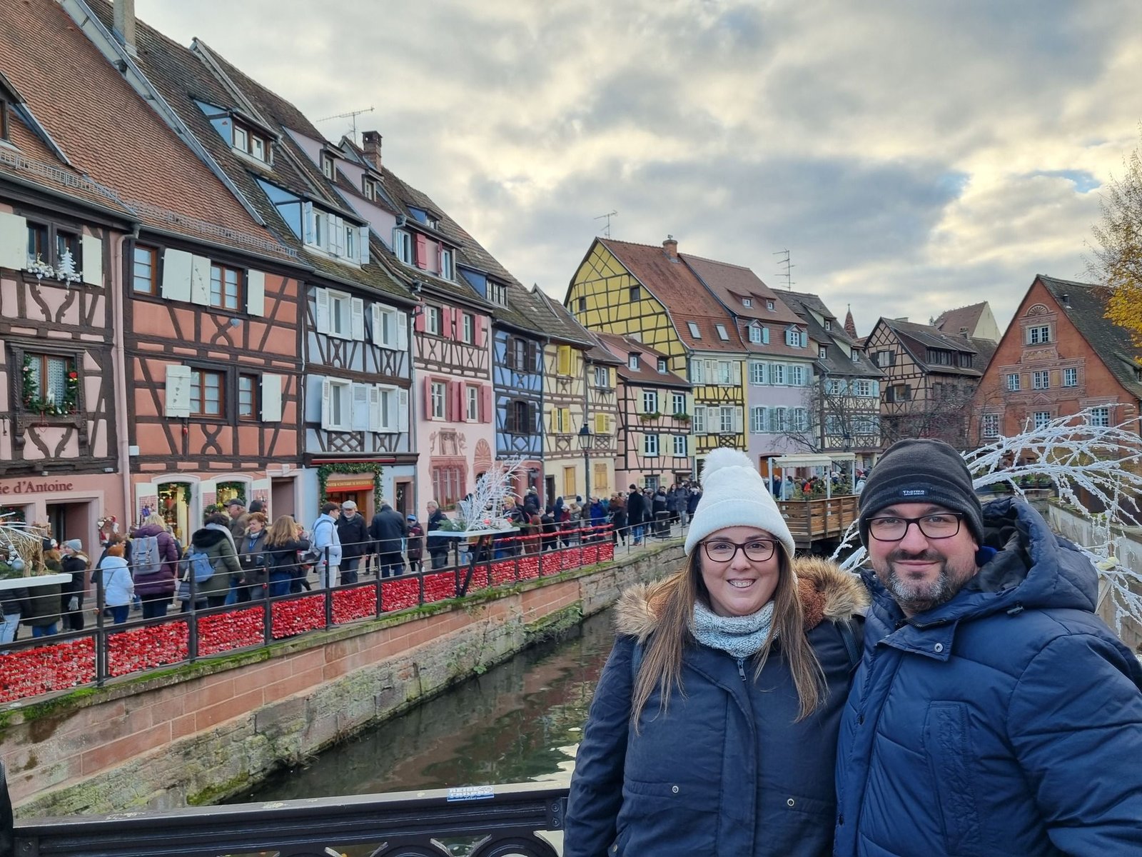 Casas de entramado iluminadas y puestos navideños junto a los canales en el mercado de Navidad de Colmar.