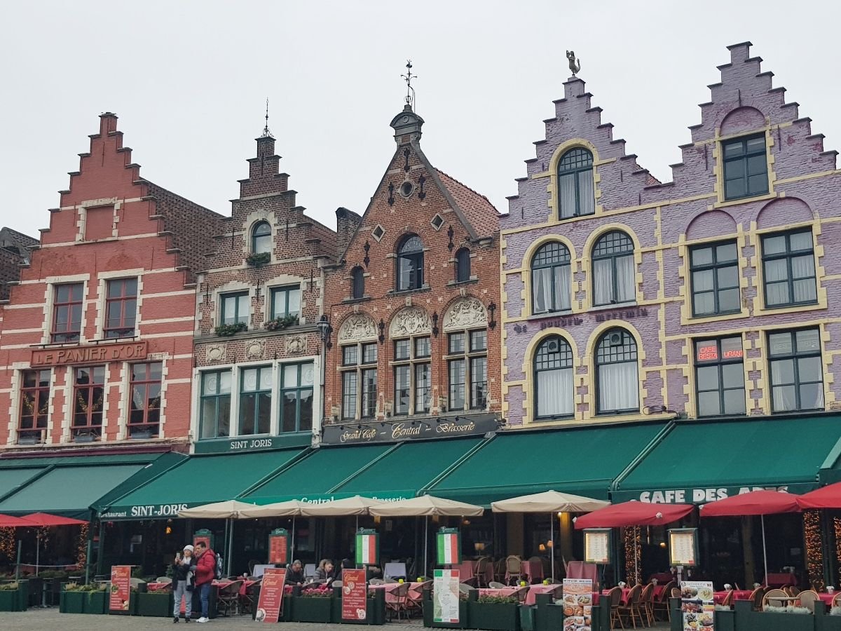 Casas medievales de colores en la Plaza Mayor de Brujas con restaurantes y terrazas