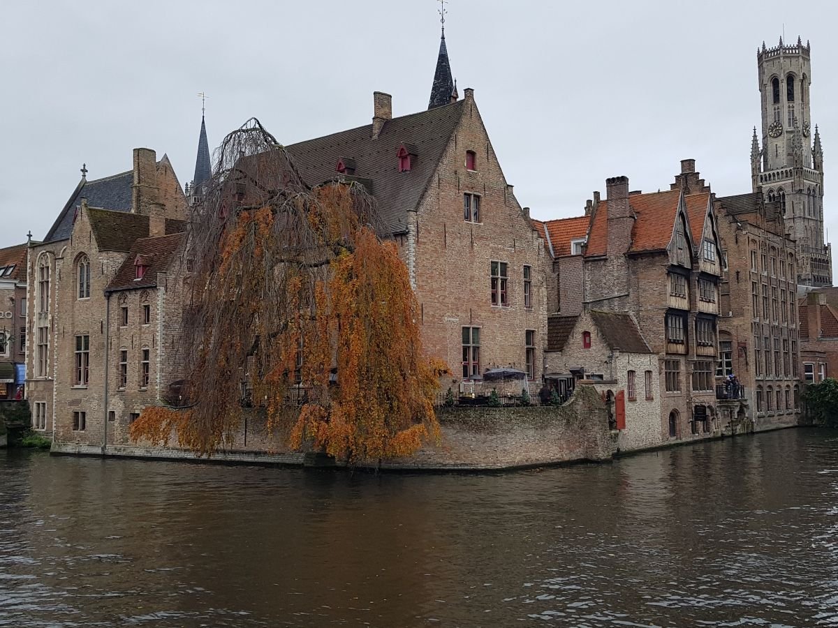 Rozenhoedkaai en Brujas con edificios medievales junto al canal y la torre Belfort al fondo