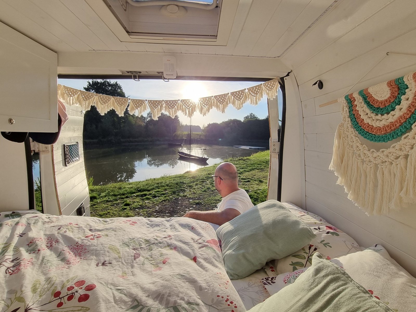 Interior de una camper con vistas a un lago durante un viaje en pareja