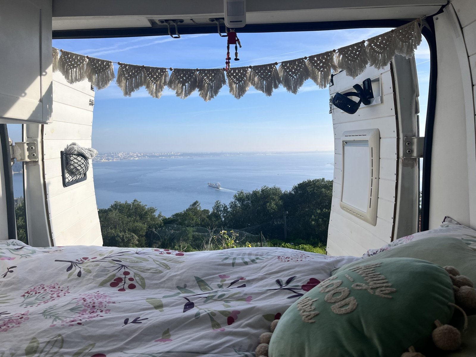 Cama dentro de una camper con vistas al mar durante un viaje por Europa