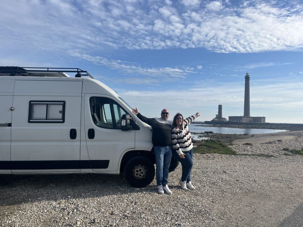 Viajar en camper en pareja junto a un faro durante una ruta por Europa