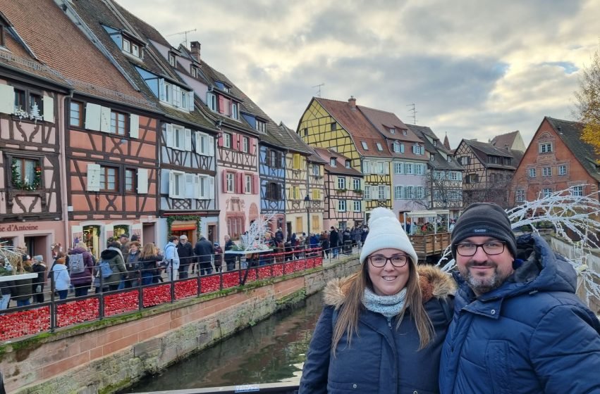 Casas de entramado iluminadas y puestos navideños junto a los canales en el mercado de Navidad de Colmar.